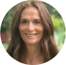 A woman with long brown hair smiles at the camera, standing outdoors with greenery in the blurred background, reflecting confidence in cybersecurity and awareness of financial crime.
